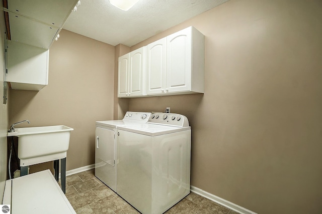 clothes washing area with cabinet space, independent washer and dryer, baseboards, and a sink