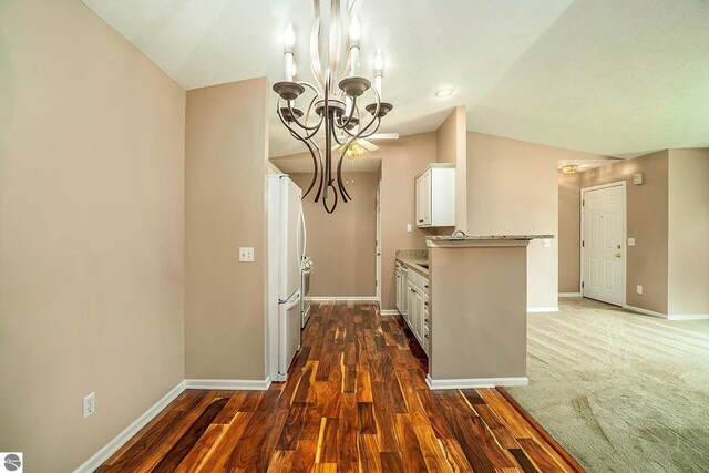 kitchen featuring an inviting chandelier, baseboards, white cabinetry, dark wood-type flooring, and freestanding refrigerator