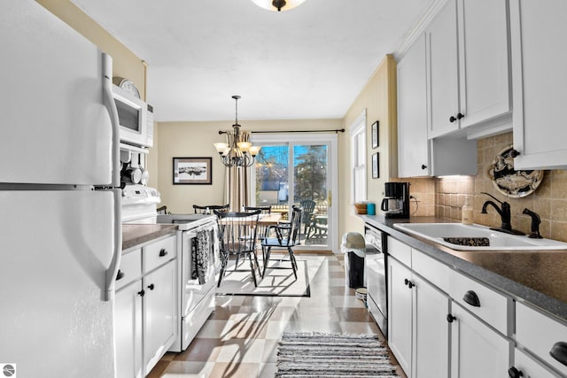 kitchen with white cabinetry, a sink, white appliances, tasteful backsplash, and a notable chandelier