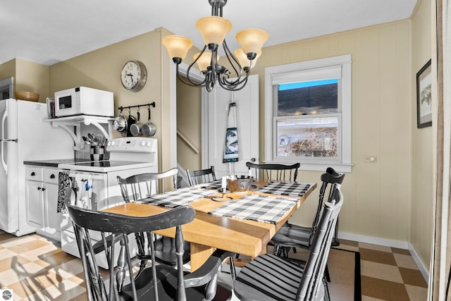 dining room with a chandelier, baseboards, and light floors