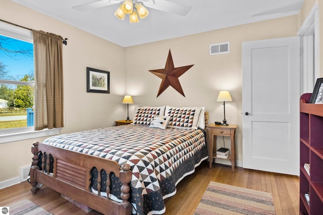 bedroom with wood finished floors, visible vents, and baseboards
