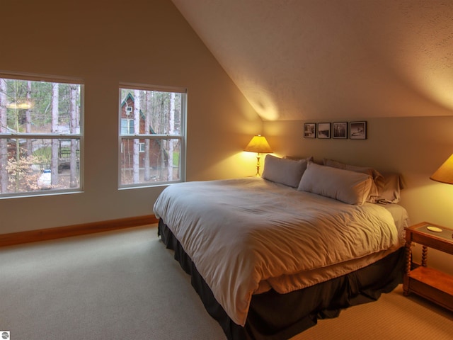 bedroom with vaulted ceiling, baseboards, and carpet floors