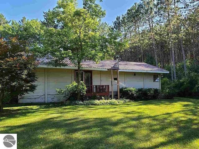 back of property featuring a lawn and metal roof