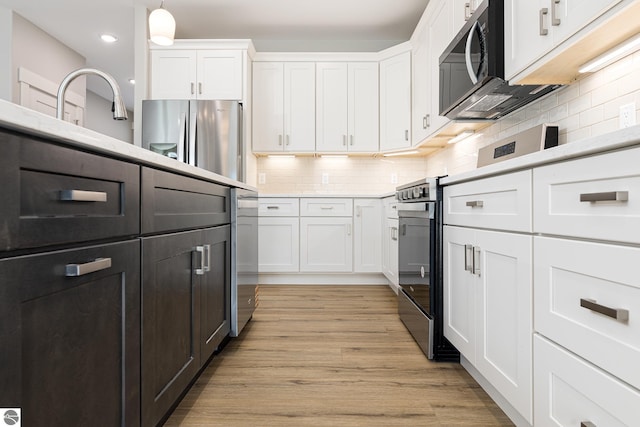 kitchen with white cabinets, stainless steel appliances, a sink, recessed lighting, and backsplash