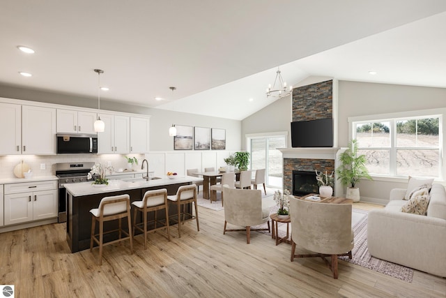 living area with lofted ceiling, an inviting chandelier, a wealth of natural light, and light wood-style floors