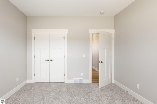 unfurnished bedroom with a closet, visible vents, carpet flooring, and baseboards