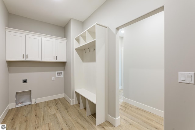 clothes washing area featuring hookup for a washing machine, electric dryer hookup, cabinet space, light wood-style flooring, and baseboards