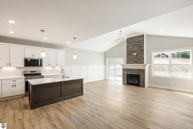 kitchen featuring white cabinets, stainless steel appliances, light countertops, a sink, and light wood-style flooring