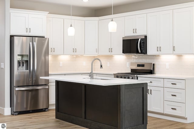 kitchen with light countertops, a sink, light wood-type flooring, tasteful backsplash, and appliances with stainless steel finishes