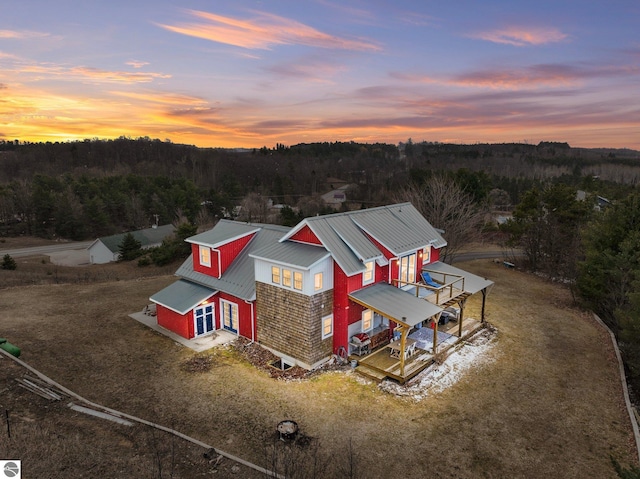 aerial view at dusk featuring a wooded view