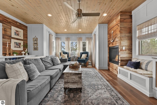 living area featuring wooden walls, ceiling fan, wooden ceiling, dark wood-type flooring, and recessed lighting