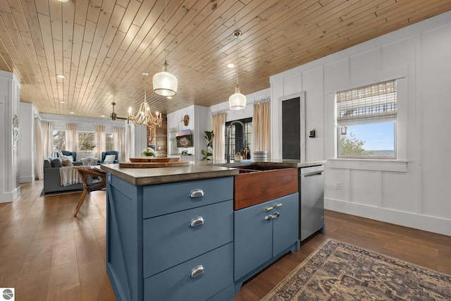 kitchen with stainless steel dishwasher, a sink, blue cabinets, open floor plan, and a notable chandelier