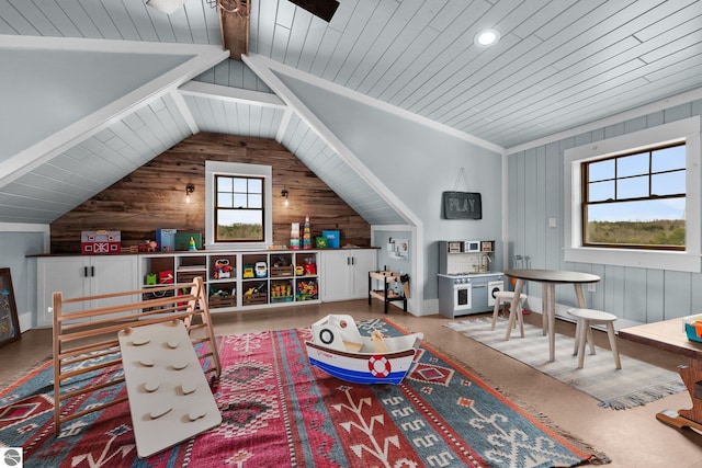 playroom featuring lofted ceiling, wood walls, wooden ceiling, and a ceiling fan