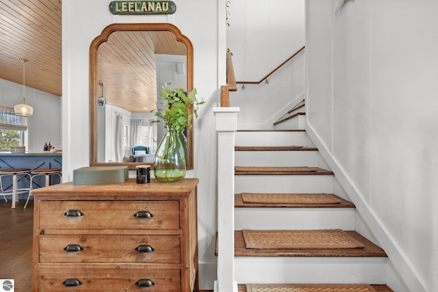 staircase with wood ceiling and wood finished floors