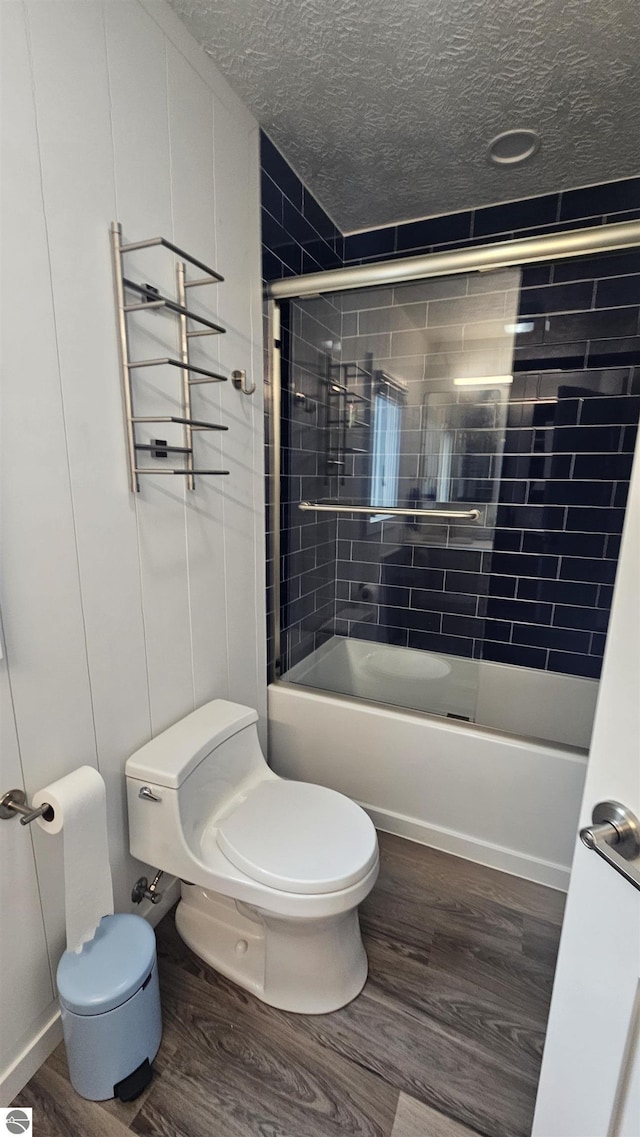 745 S Crescent Ave, Au Gres, MI 48703 - bathroom featuring a textured ceiling, combined bath / shower with glass door, wood finished floors, and toilet