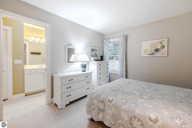 bedroom with ensuite bath, a sink, and light colored carpet