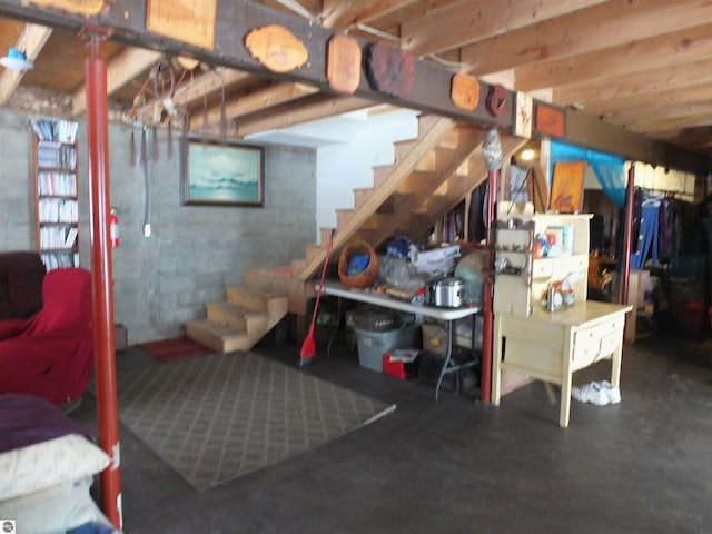 basement featuring concrete block wall and stairway
