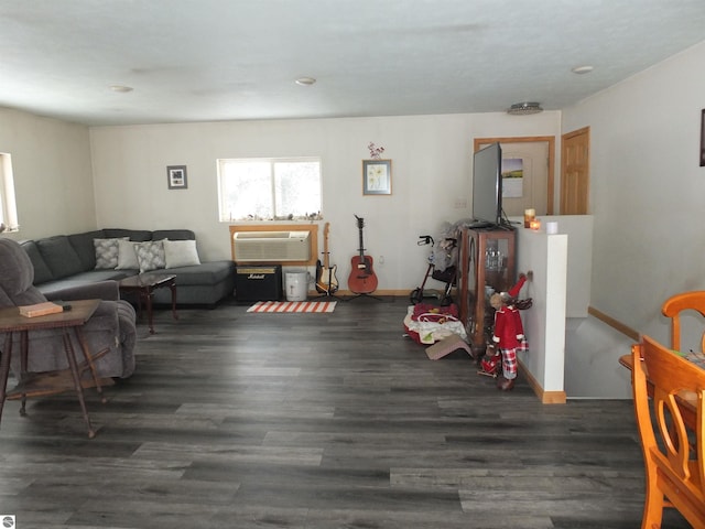 living area with wood finished floors, an AC wall unit, and baseboards