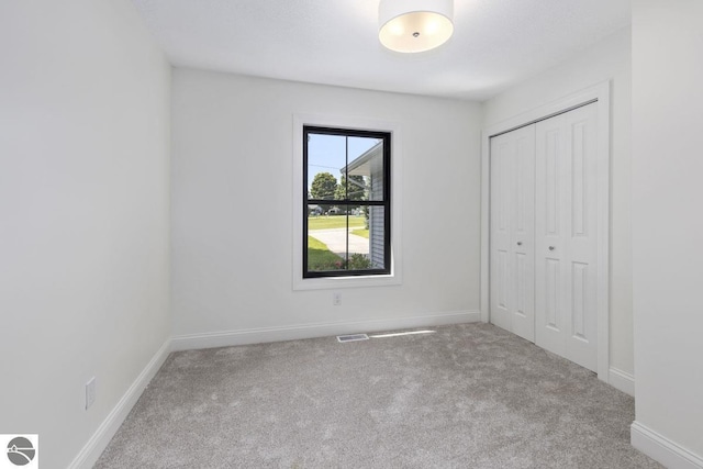 unfurnished bedroom featuring baseboards, carpet flooring, and a closet