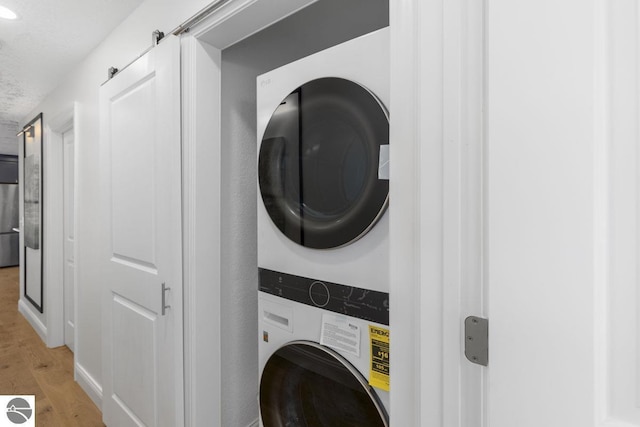 laundry area with stacked washing maching and dryer, laundry area, and light wood-style floors