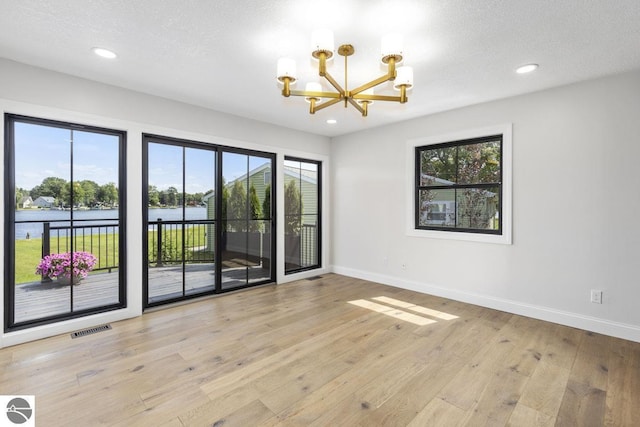 empty room featuring baseboards, an inviting chandelier, visible vents, and a wealth of natural light