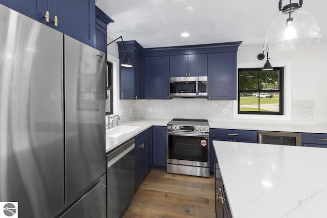 kitchen featuring blue cabinets, dark wood-style flooring, stainless steel appliances, and a sink