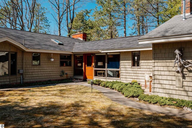 view of exterior entry featuring a shingled roof and a chimney