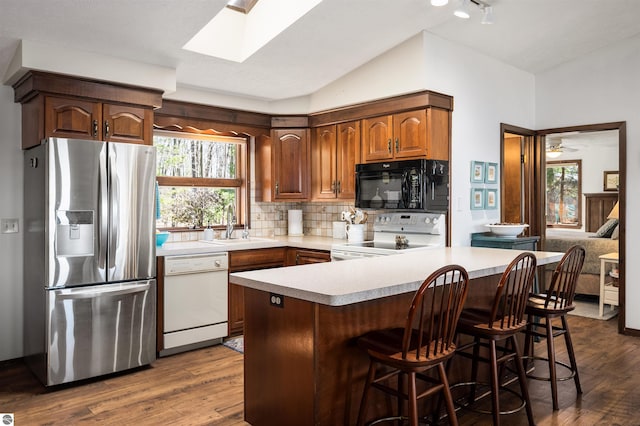kitchen featuring light countertops, dark wood finished floors, decorative backsplash, and white appliances