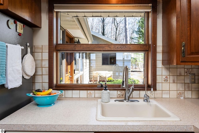 kitchen with decorative backsplash, light countertops, and a sink