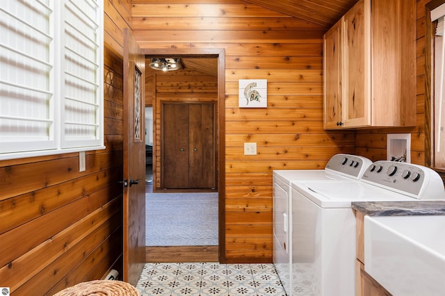 washroom featuring wood walls, cabinet space, and washer and clothes dryer