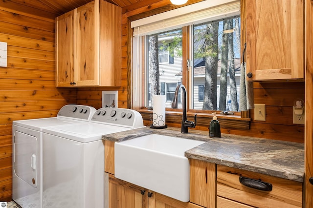 laundry area featuring separate washer and dryer, wooden walls, a sink, and cabinet space