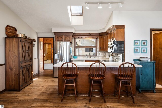 kitchen featuring a peninsula, a sink, dark wood finished floors, electric range oven, and light countertops