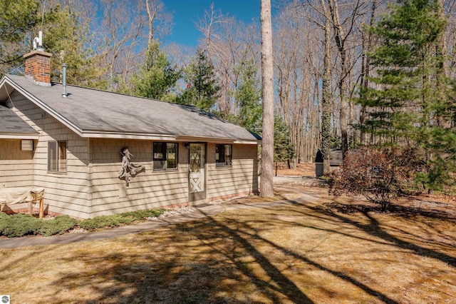 view of home's exterior featuring a shingled roof and a chimney