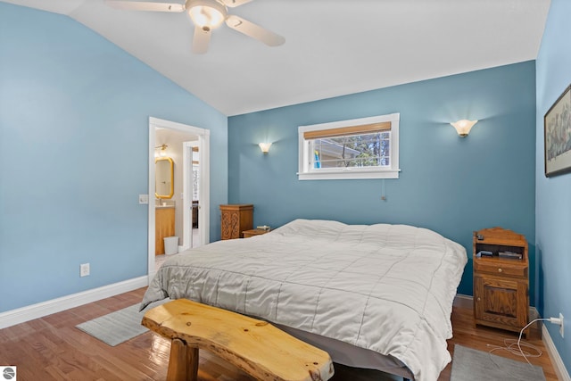 bedroom with wood finished floors, baseboards, ensuite bathroom, ceiling fan, and vaulted ceiling