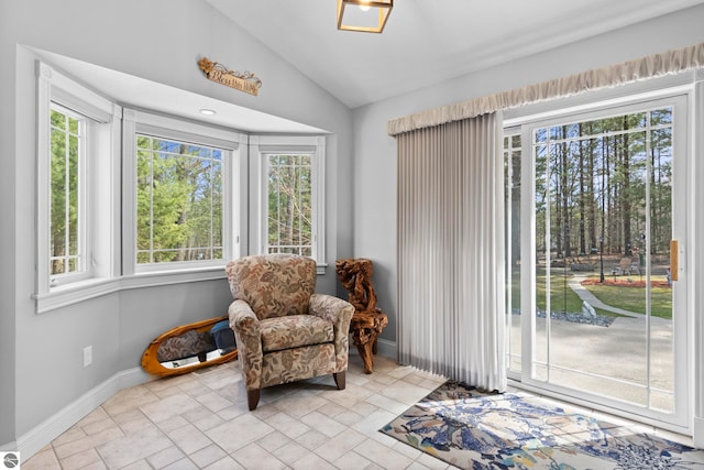 living area featuring baseboards, vaulted ceiling, and a wealth of natural light