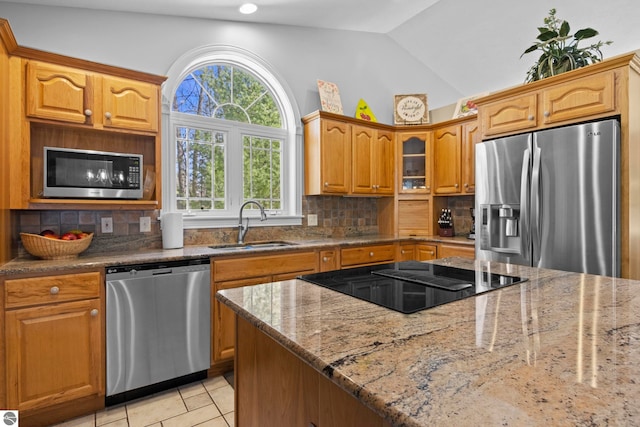 kitchen featuring a sink, appliances with stainless steel finishes, decorative backsplash, and light stone countertops