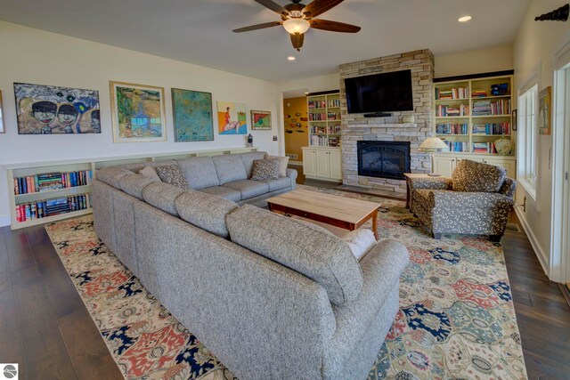 living area featuring a ceiling fan, a stone fireplace, recessed lighting, and dark wood-style floors
