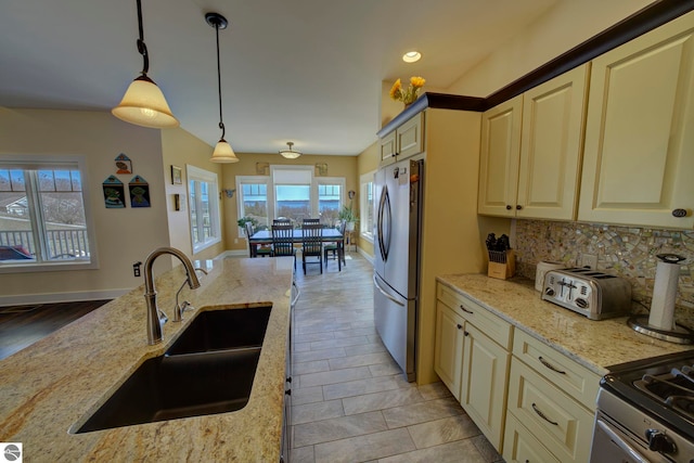 kitchen with a healthy amount of sunlight, a sink, hanging light fixtures, and freestanding refrigerator
