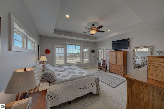 bedroom featuring a tray ceiling, recessed lighting, light colored carpet, and multiple windows