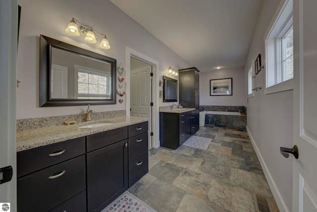 bathroom with baseboards, a sink, and a healthy amount of sunlight