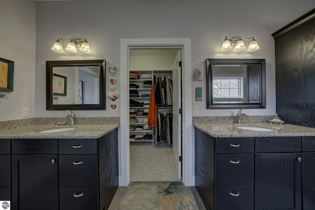 full bathroom with two vanities, a sink, and a spacious closet