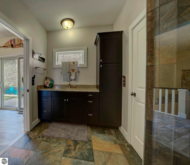 interior space featuring baseboards, stone tile floors, and vanity