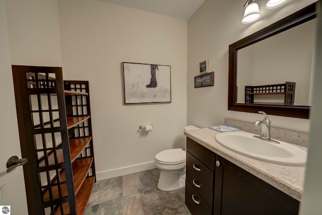 bathroom featuring baseboards, vanity, and toilet