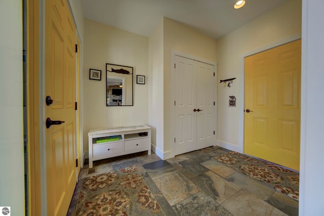 entrance foyer with baseboards, stone finish flooring, and recessed lighting