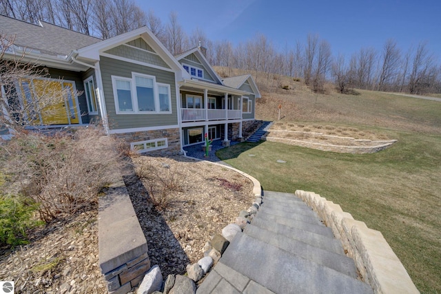 view of home's exterior with stairway, stone siding, and a yard