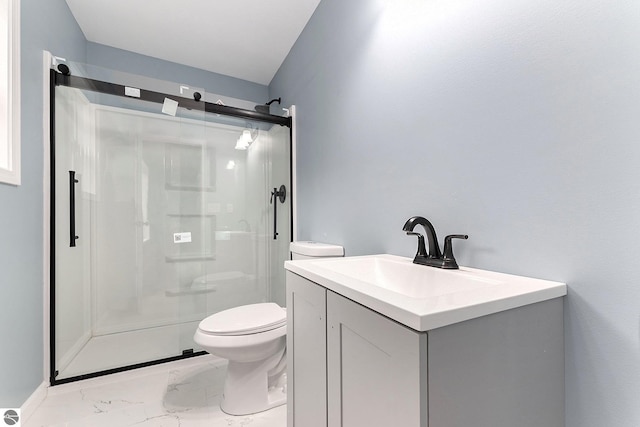 bathroom featuring marble finish floor, toilet, vanity, and a stall shower