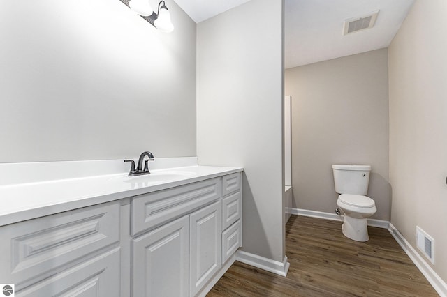 bathroom with wood finished floors, visible vents, toilet, and vanity