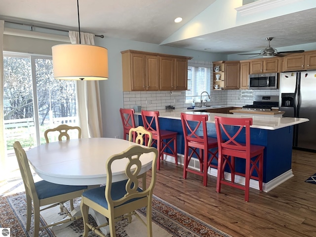 2708 Ruby St, Traverse City, MI 49684 - kitchen featuring appliances with stainless steel finishes, backsplash, vaulted ceiling, dark wood-style flooring, and a kitchen bar