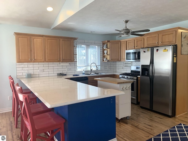 2708 Ruby St, Traverse City, MI 49684 - kitchen with stainless steel appliances, a sink, a peninsula, a kitchen breakfast bar, and wood finished floors