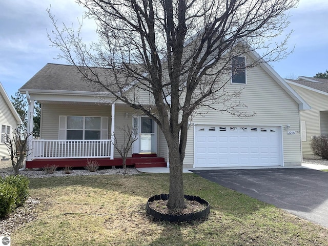 2708 Ruby St, Traverse City, MI 49684 - view of front of property featuring asphalt driveway, a garage, a porch, a front yard, and a shingled roof